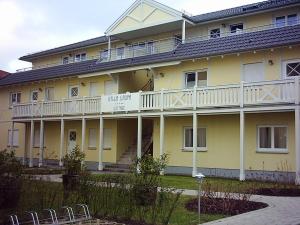 um grande edifício amarelo com uma varanda e cadeiras em Ferienwohnung Oase102 em Kühlungsborn