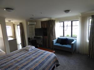 a hotel room with a bed and a couch and window at Sahara Motels in Dunedin