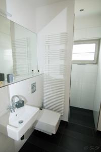 a white bathroom with a sink and a shower at Ostsee - Reetdachhaus Nr 9 "Emma" im Strand Resort in Heiligenhafen