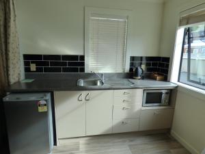 a small kitchen with a sink and a microwave at Sahara Motels in Dunedin