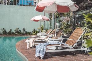 uma fila de cadeiras e guarda-sóis ao lado de uma piscina em The Island Gold Coast em Gold Coast