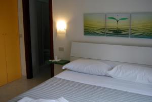 Un dormitorio con una cama blanca con una foto en la pared en Albergo Belvedere, en Ventotene