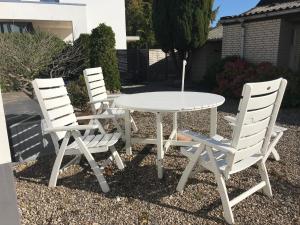 3 sillas blancas y una mesa y sillas blancas en Landhaus zur Seebrücke Nr 2, en Dahme
