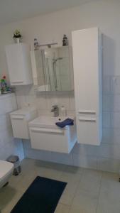 a white bathroom with a sink and a mirror at Ferienwohnung Ihle in Heiligenhafen