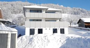 a white house in the snow with a pile of snow at VILLA BERGAUF, Studio Apartment Kaiserin Elisabeth Sisi INKL KÖNIGSCARD !! in Hohenpeißenberg