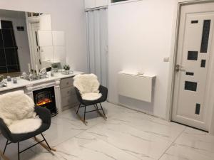 a white kitchen with two chairs and a fireplace at Duplex Marquis in Braşov +22 photos