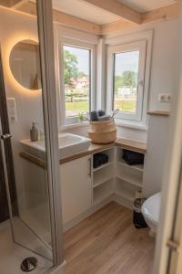a small bathroom with a sink and two windows at Huxfeld-Hof - Tiny-House MOORitz in Grasberg