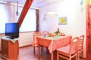 uma sala de jantar com uma mesa e cadeiras e uma televisão em Landglück em Klausdorf