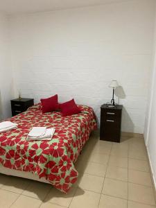 a bedroom with a bed with red sheets and red pillows at Departamento Tafí Viejo in Tafí Viejo
