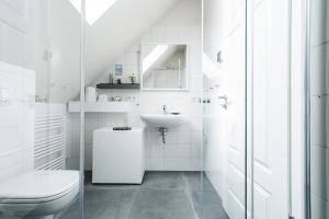 a white bathroom with a toilet and a sink at Whg 16 - Sol in Zingst