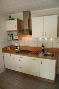 a kitchen with white cabinets and a sink at Ferienhaus 3370 in Tossens in Butjadingen OT Tossens