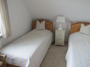 a bedroom with two beds and a night stand with a lamp at DHH Wiesenstraße 55 - Dünensand in Zingst