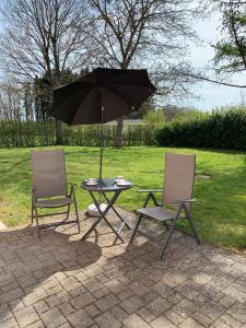 2 chaises et une table avec un parasol dans l'établissement Eifel Holiday, à Prüm