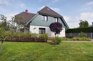 a green and white house with a yard at Kranichguck, App 2 in Zingst