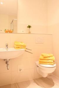 ein Badezimmer mit einem Waschbecken und einem WC mit gelben Handtüchern in der Unterkunft L3 - Ferienanlage Lindenstraße 1 - FERIENDOMIZIL HOLLICH in Grömitz