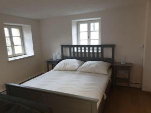 um quarto com uma cama com lençóis brancos e 2 janelas em Torhaus Rattelsdorf - Wohnung Lilie em Rattelsdorf