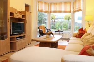 ein Wohnzimmer mit einem Sofa und einem TV in der Unterkunft Haus am Grömitzer Deich - Whg 4 in Grömitz