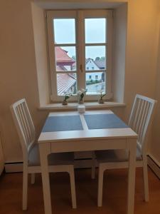 a dining room table with two chairs and a window at Torhaus Rattelsdorf - Wohnung Lilie in Rattelsdorf