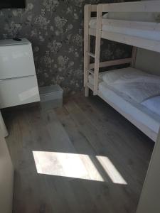 a bedroom with two bunk beds and a wooden floor at Fehmarn-OstseeferienStrandresidenz VogelflugApp 10 in Fehmarnsund