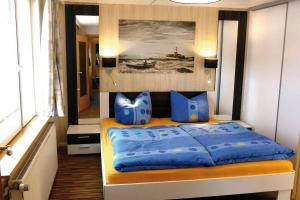 a bedroom with a bed with blue pillows and a painting at Achterdeck FW 2 in Zingst