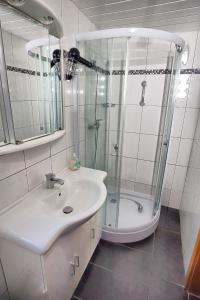 a white bathroom with a shower and a sink at Achterdeck FW 2 in Zingst