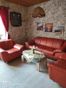 a living room with red leather couches and a table at Fewo 1 in Sassnitz