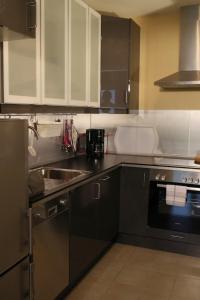 uma cozinha com armários pretos, um lavatório e um fogão em Kamaahr em Friedenstal