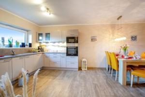 a kitchen with white cabinets and a table with yellow chairs at Wellness - Ferienhaus Küstenwind in Klausdorf