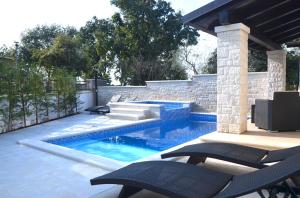 a swimming pool with two chairs and a patio at Villa Bavaria Porec in Rošini