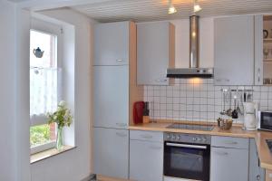a kitchen with white cabinets and a stove top oven at Am Hinrichsberg unten in Staberdorf