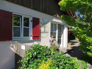 une maison avec une porte rouge et quelques plantes dans l'établissement Ferienwohnung Vöst, à Peiting