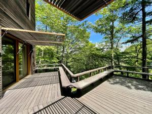 a wooden deck with a bench on the side of a house at 軽井沢 - Karuizawa Villa H24 - ペット可 - 条件付き小型犬OK in Oiwake