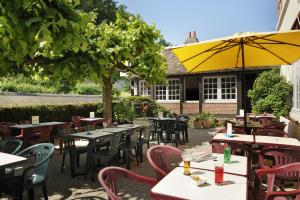 um restaurante ao ar livre com mesas e cadeiras e um guarda-sol amarelo em Hostellerie Du Chateau em Chaumont-sur-Loire