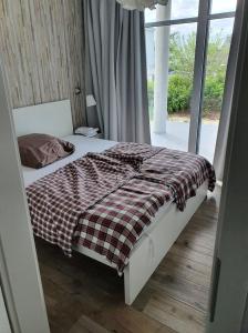 a bed with a checkered blanket in a room with a window at Fehmarn-OstseeferienStrandresidenz VogelflugApp 9 in Fehmarnsund