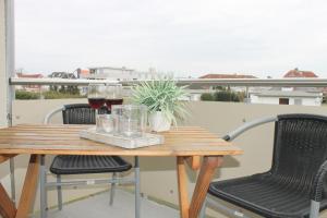 - une table en bois avec deux verres de vin sur le balcon dans l'établissement "Haus Wiking - Whg 14" - strandnah und ruhig gelegen, à Grömitz