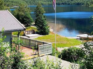 a house with a flag pole next to a lake at 8 person holiday home in j rpeland in Jørpeland