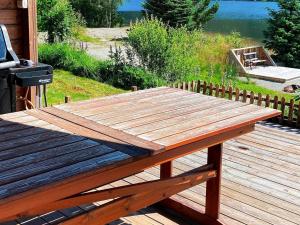 a wooden picnic table on a deck next to a lake at 8 person holiday home in j rpeland in Jørpeland