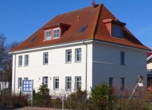 uma grande casa branca com um telhado vermelho em Ferienwohnung Uferschwalbe em Rerik