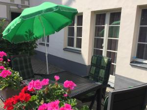 un parasol vert assis sur une table avec des fleurs dans l'établissement Apartment mit Terrasse No1, à Quedlinbourg