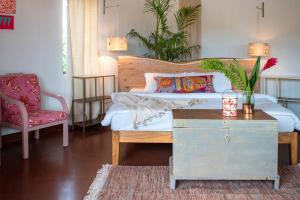 a bedroom with a bed with a table and a chair at StayVista at Boho Banyan with Pvt Pool & Garden in Alibaug