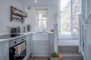 uma cozinha branca com um lavatório e uma janela em Brook Cottage - 1 Bedroom Cottage - Dale em Dale