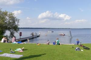 eine Gruppe von Menschen, die am Ufer eines Sees sitzen in der Unterkunft Frietied am Wittensee in Bünsdorf