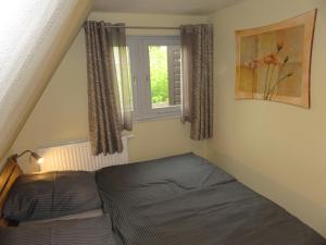 Schlafzimmer mit einem Bett und einem Fenster in der Unterkunft Frietied am Wittensee in Bünsdorf