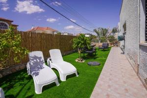 a yard with two white chairs and a fence at YalaRent Green Garden Villa with Private Pool in Eilat