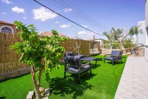 a garden with chairs and a table and a tree at YalaRent Green Garden Villa with Private Pool in Eilat