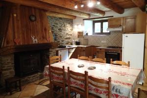 a kitchen with a table and a refrigerator and a fireplace at artiguelongue grange restaurée in Loudenvielle