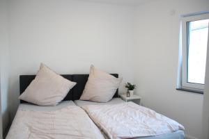 a bed with white sheets and pillows in a room at Casa Kronengarten Nr 6 in Hilden