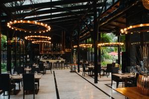 Un restaurante con mesas, sillas y lámparas de araña. en Cross Chiang Mai Riverside, en Chiang Mai