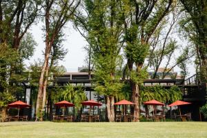 a group of tables with red umbrellas in front of a building at Cross Chiang Mai Riverside in Chiang Mai