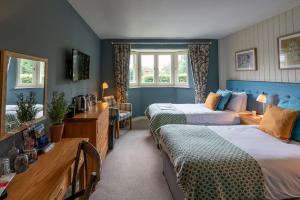 2 łóżka w pokoju z niebieskimi ścianami w obiekcie The Bird In Hand w mieście Maidenhead